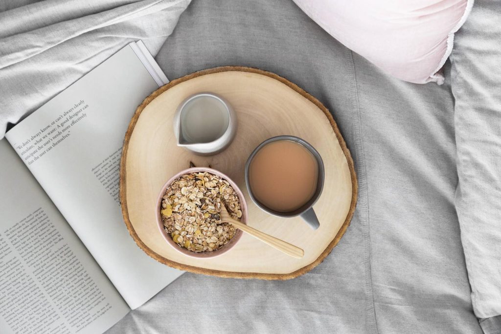 breakfast on wooden tray with magazine and bedding