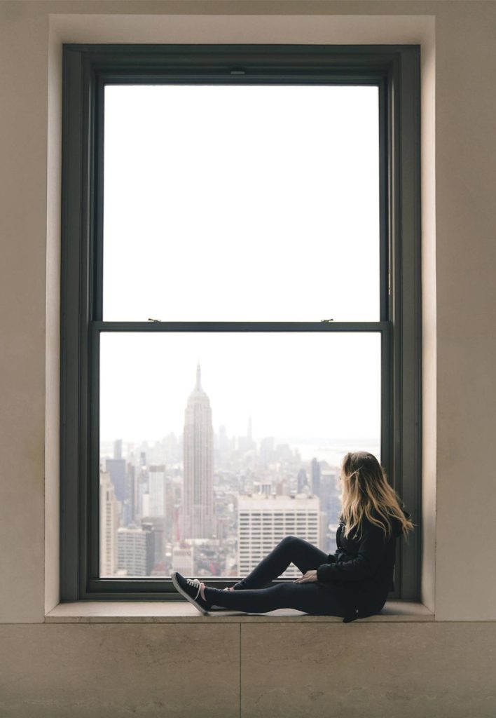 woman sat on a ledge gazing out of the window