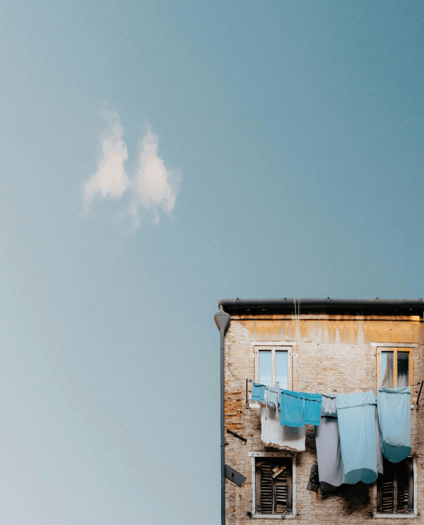 top of a worn house with a washing line of blue laundry across the front